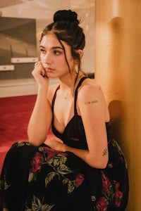 a woman in a floral dress sitting on a pillar