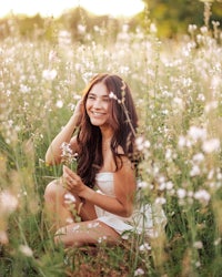 a young woman sitting in a field of flowers