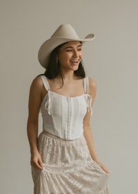 a woman wearing a white cowboy hat and lace skirt