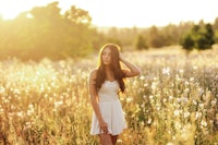 a woman in a white dress standing in a field