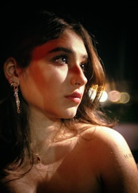 a young woman in a dark room with earrings