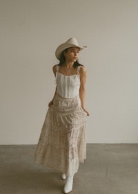 a woman wearing a cowboy hat and lace skirt